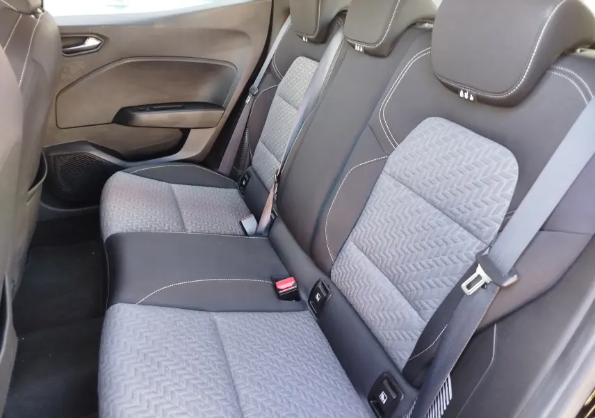 Vue latérale droite de l’arrière de la Renault Clio 1.6 E-Tech 140ch Limited 2022, sièges tissu gris et noir avec surpiqûres blanches.