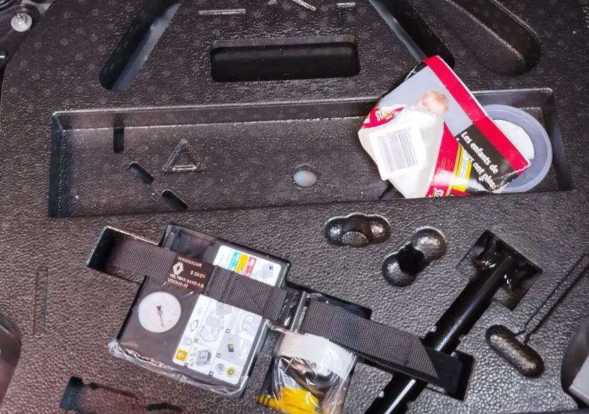 Vue rapprochée du coffre de la Renault Clio 1.6 E-Tech 140ch Limited noir étoile, montrant le kit de réparation pneus et rangement intégré.