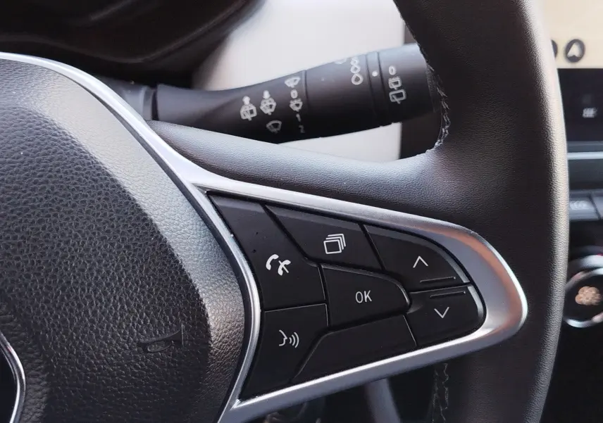 Gros plan sur les commandes au volant côté gauche de la Renault Clio 1.6 E-Tech noir étoile, avec boutons multifonctions et levier d’essuie-glace.