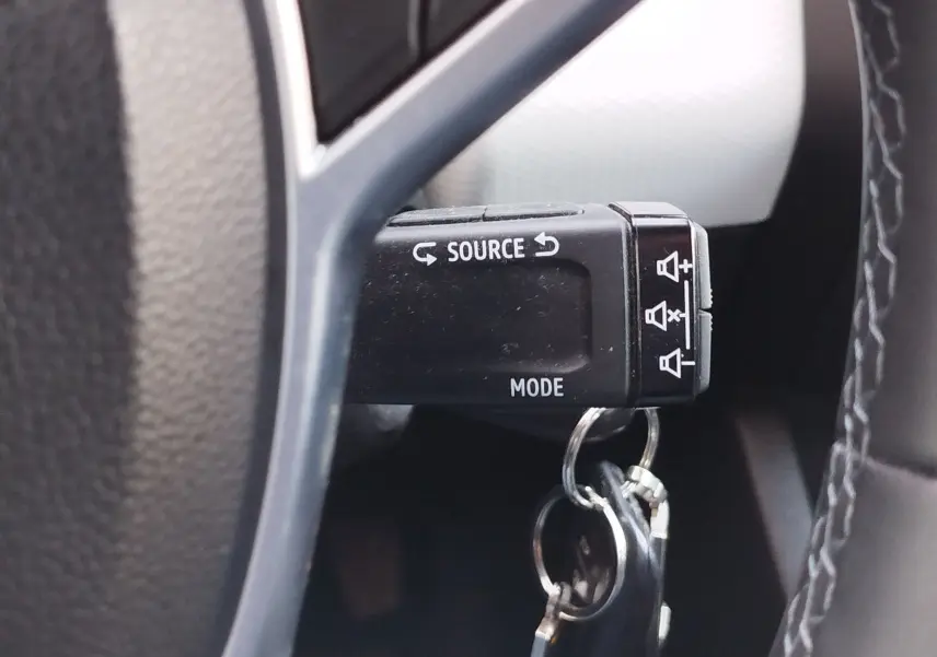 Gros plan sur la commande au volant noir de la Renault Clio 1.6 E-Tech 2022 avec clés accrochées, bouton Source et Mode visibles.