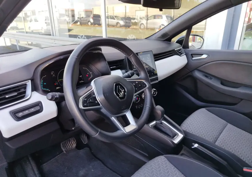 Vue intérieure côté conducteur de la Renault Clio 1.6 E-Tech 140ch Limited 2022 avec tableau de bord noir et inserts blancs.
