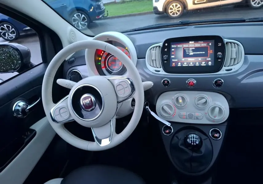 Intérieur de la Fiat 500 2022 Gris Electroclash, vue du poste de conduite avec volant blanc et tableau de bord moderne.