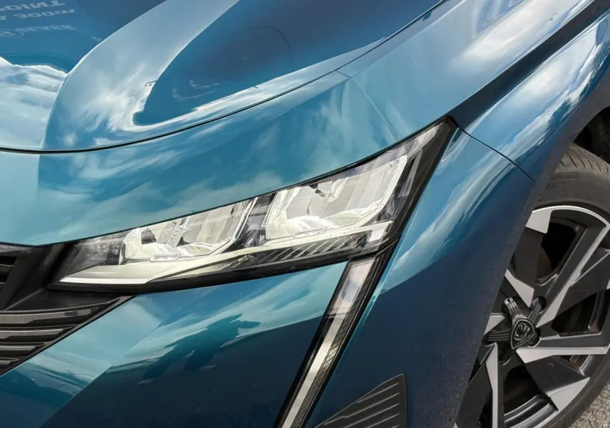 Gros plan sur le phare avant droit et la jante alliage 17'' d’une Peugeot 308 Bleu Obsession 2024.