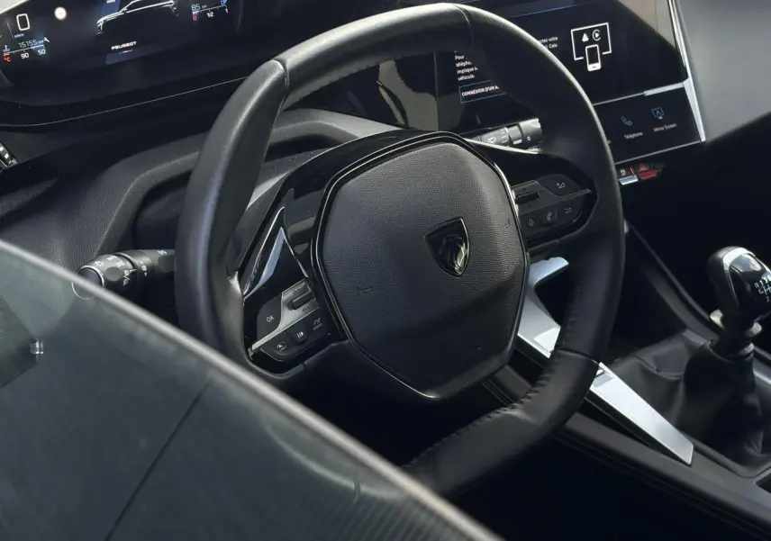 Vue rapprochée du volant cuir noir et du levier de vitesse manuel dans l’habitacle d’une Peugeot 308 2024.