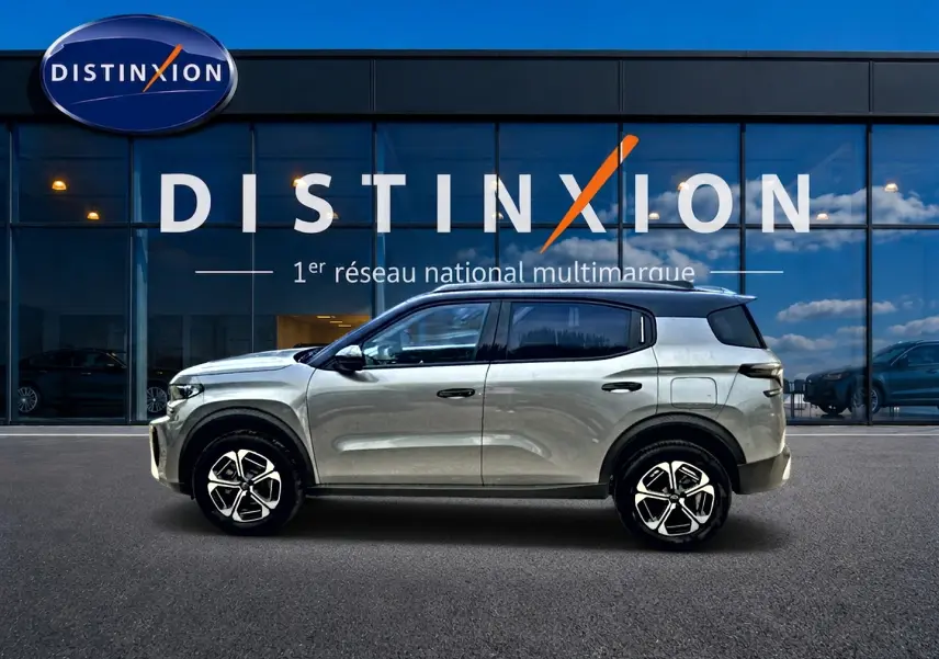 Vue profil droit du Citroën C3 Aircross 2026 gris mercury avec jantes alu et toit noir devant un showroom Distinxion.
