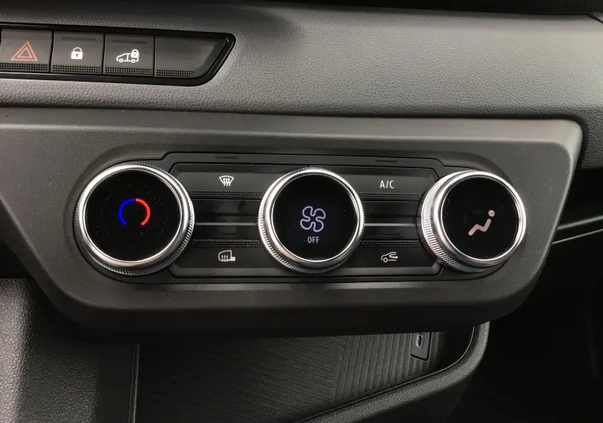 Vue rapprochée des commandes de climatisation du tableau de bord du Renault Master blanc 2025, avec réglages circulaires.