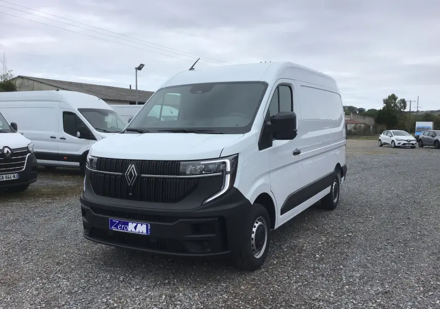 Renault Master blanc en 3/4 avant droit sur un parking, avec calandre noire et logo Renault visible.