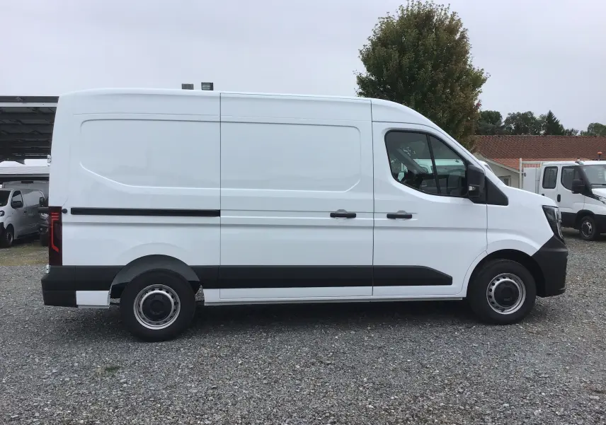 Profil côté gauche du fourgon blanc Renault Master L2H2 2025 avec bande noire et roues acier visibles.