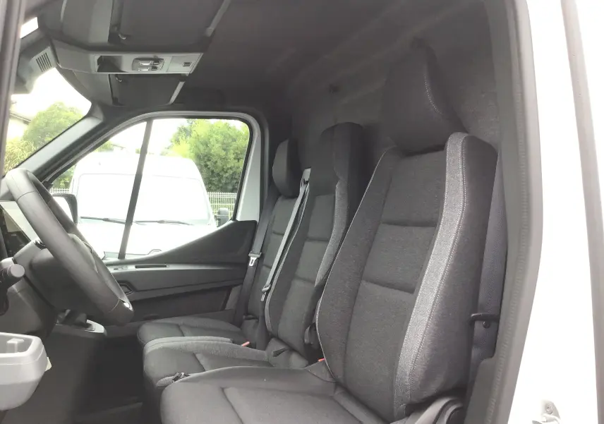Intérieur du Renault Master blanc vu côté conducteur, montrant les sièges avant gris et la banquette passager triple.