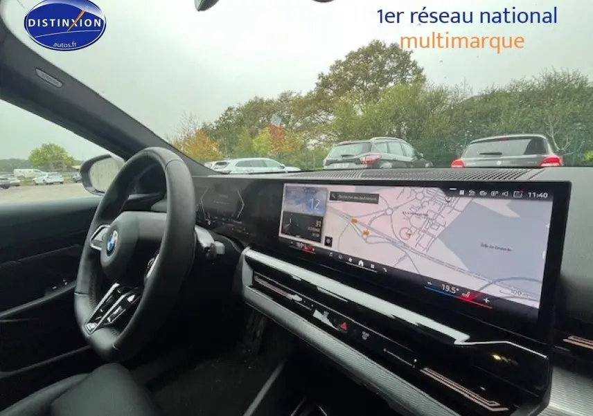 Vue intérieure du tableau de bord et volant cuir noir d'une BMW Série 5 gris, avec écran tactile GPS large.
