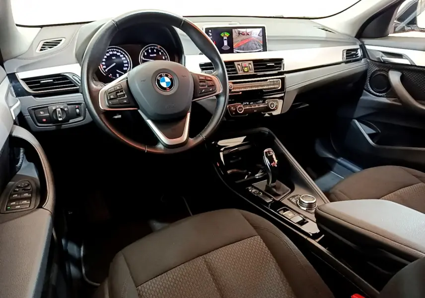 Vue intérieure avant droite du BMW X2 2023 avec tableau de bord noir, volant cuir multifonctions et écran central couleur.