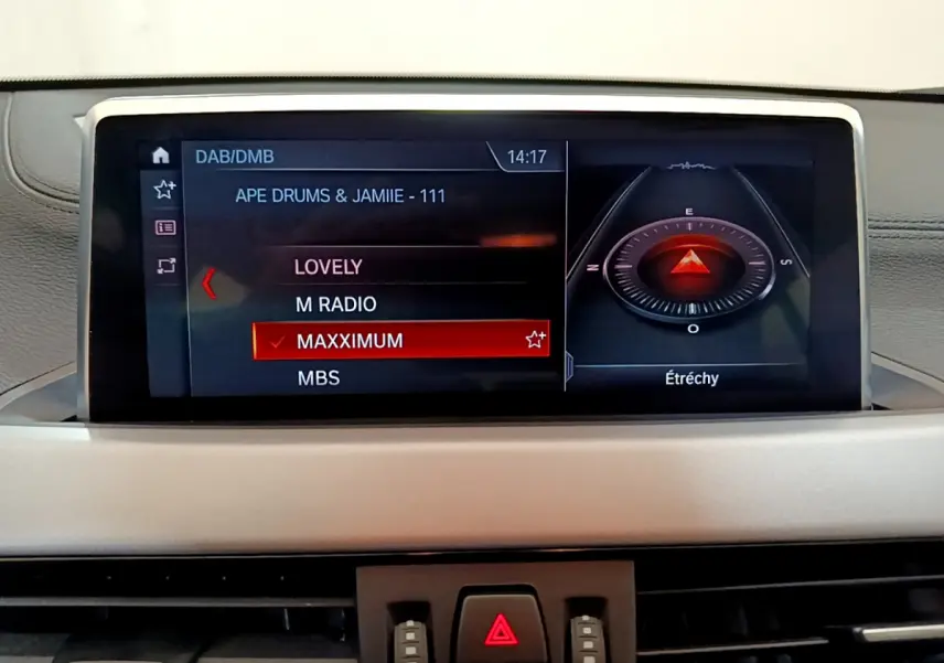 Écran central du tableau de bord du BMW X2 blanc 2023 affichant la radio et la boussole numérique.