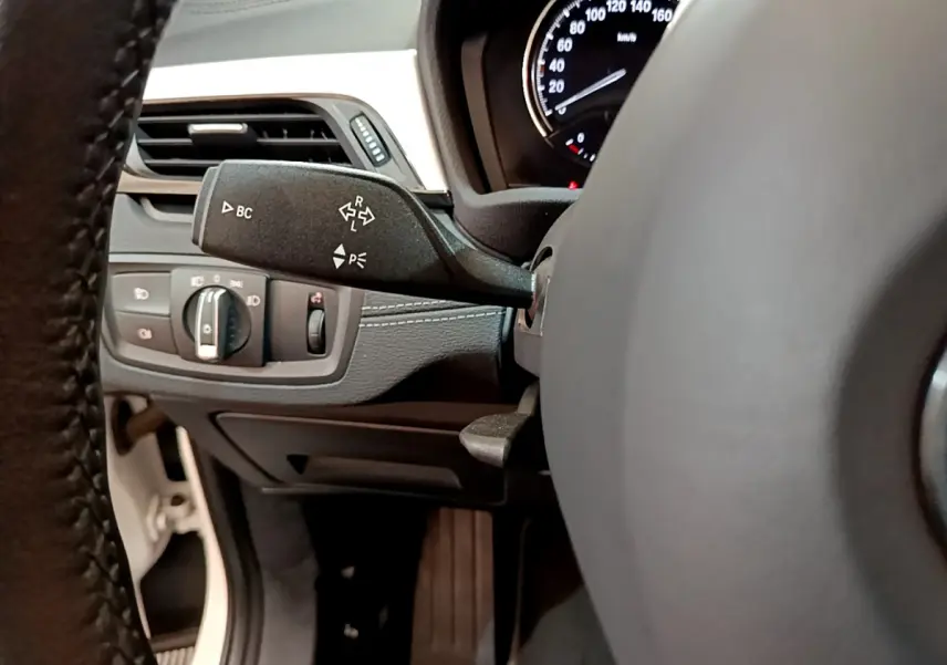 Gros plan sur la commande de clignotants à gauche du volant dans le tableau de bord noir du BMW X2 blanc 2023.