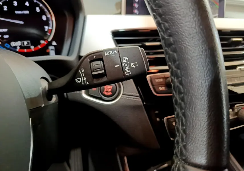 Gros plan sur la commande d’essuie-glace à gauche du volant cuir noir dans l’habitacle du BMW X2 blanc 2023.