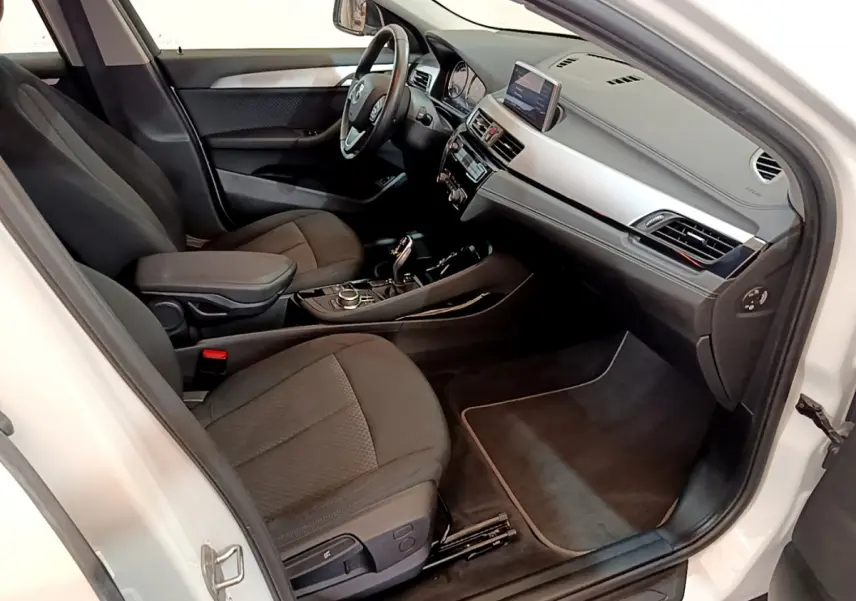 Intérieur noir du BMW X2 sDrive18i 2023 vu côté passager, avec tableau de bord moderne et écran central.