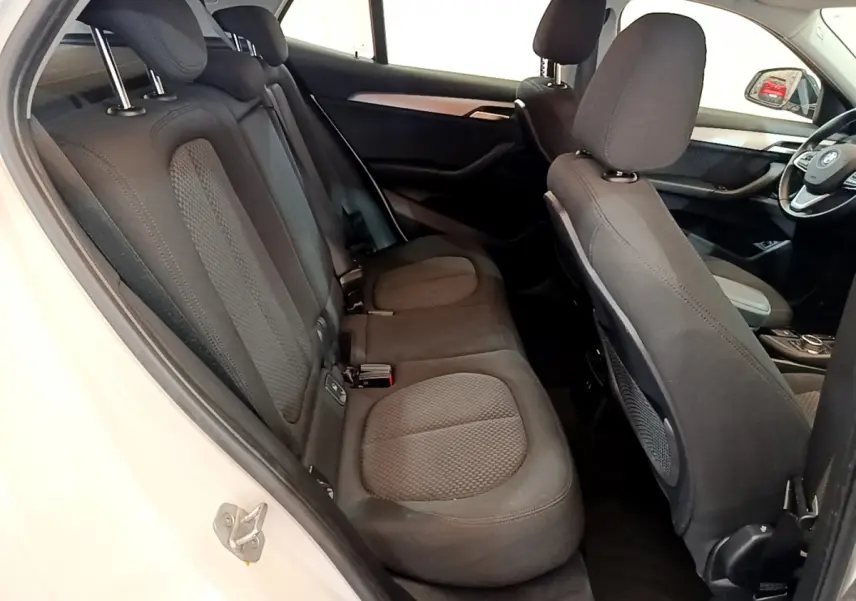 Intérieur de la BMW X2 blanc, vue latérale côté gauche sur la banquette arrière et le tableau de bord avant.
