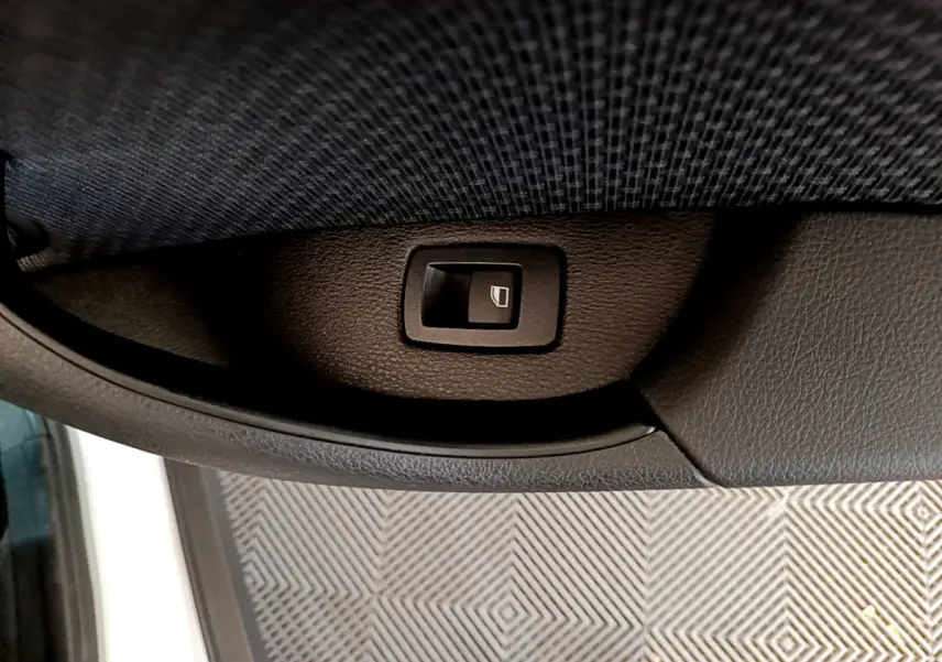 Bouton de commande de lève-vitre intégré dans la garniture intérieure côté gauche d'une BMW X2 blanche 2023.
