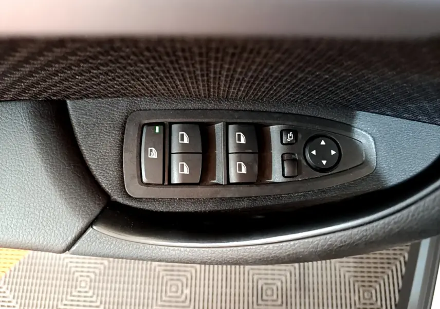 Panneau de commandes des vitres et rétroviseurs côté conducteur dans une BMW X2 blanc 2023.