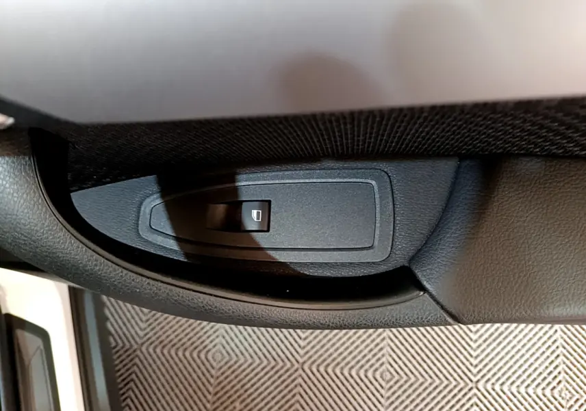 Bouton de commande de lève-vitre côté conducteur dans l'intérieur noir d'une BMW X2 blanc 2023.