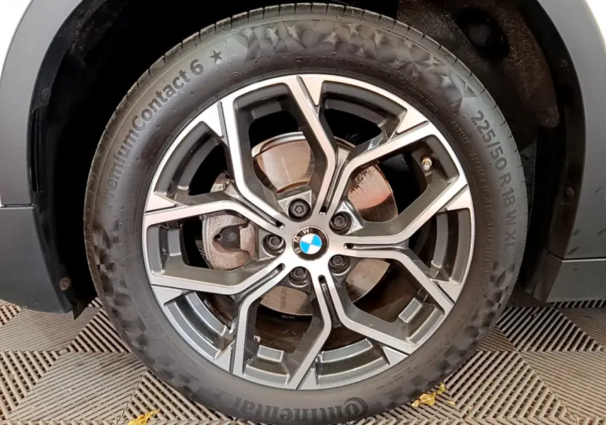 Gros plan sur la roue avant droite du BMW X2 blanc 2023, mettant en valeur la jante alliage et le logo BMW central.