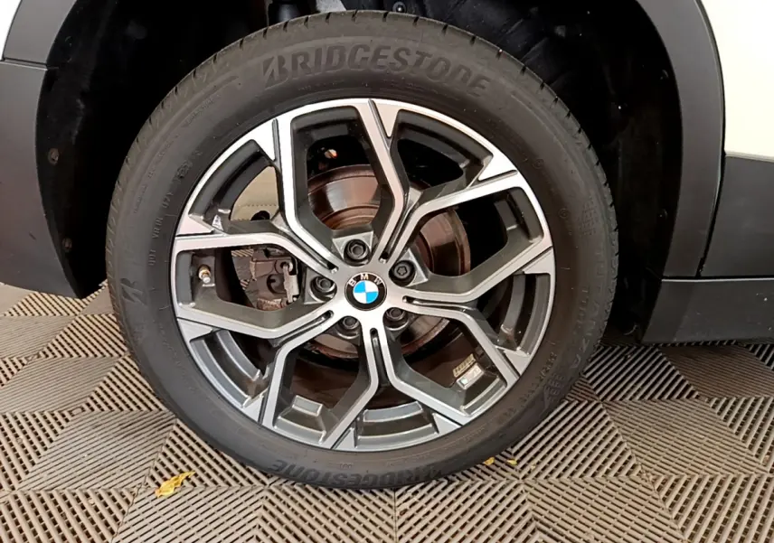 Gros plan sur la roue avant droite du BMW X2 blanc 2023, mettant en valeur la jante alliage et le pneu Bridgestone.