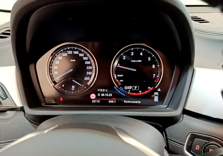Tableau de bord numérique de BMW X2 blanc 2023, vue centrée sur les compteurs vitesse et régime moteur.