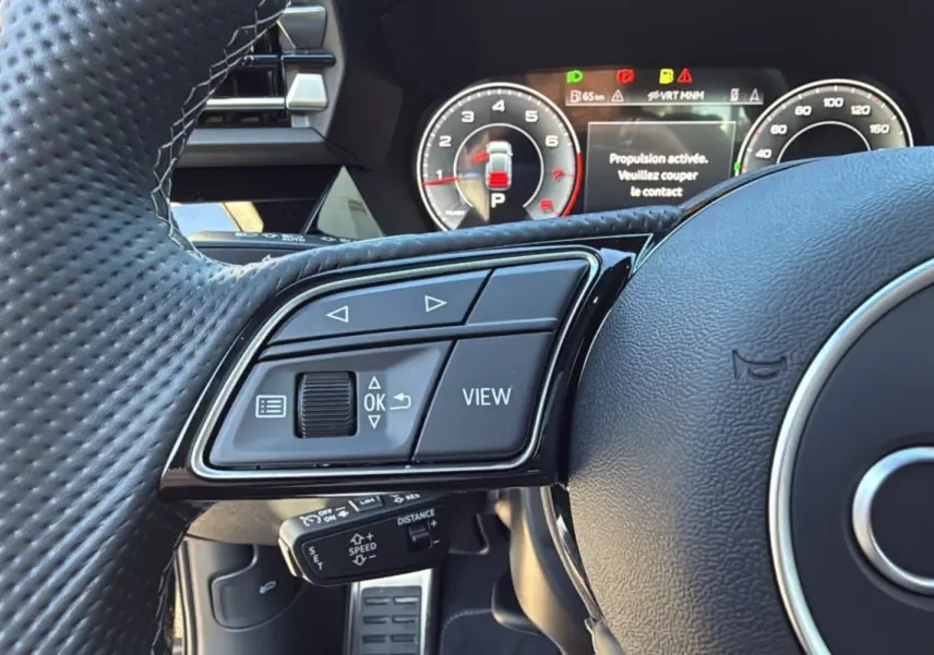 Gros plan sur le volant cuir à méplat de l'Audi A3 2025 avec commandes multifonctions et tableau de bord numérique.