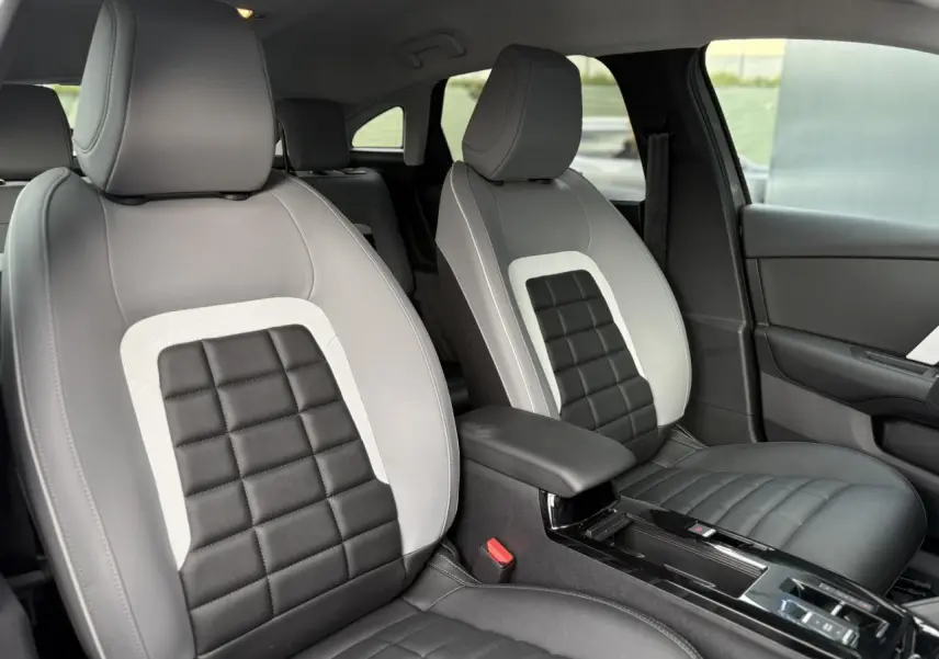 Vue intérieure rapprochée des sièges avant gris clair et noir avec accoudoir central de la Citroën C4 Hybrid 2025.