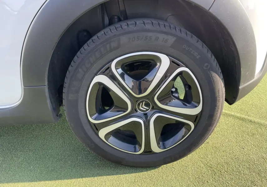 Gros plan sur la roue avant gauche blanche banquise d'une Citroën C3 III avec jante noire et chrome brillant.