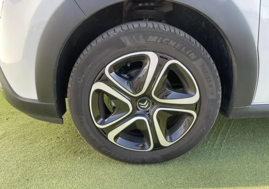 Gros plan sur la roue avant gauche d'une Citroën C3 blanche avec jante alliage noire et argentée au design moderne.