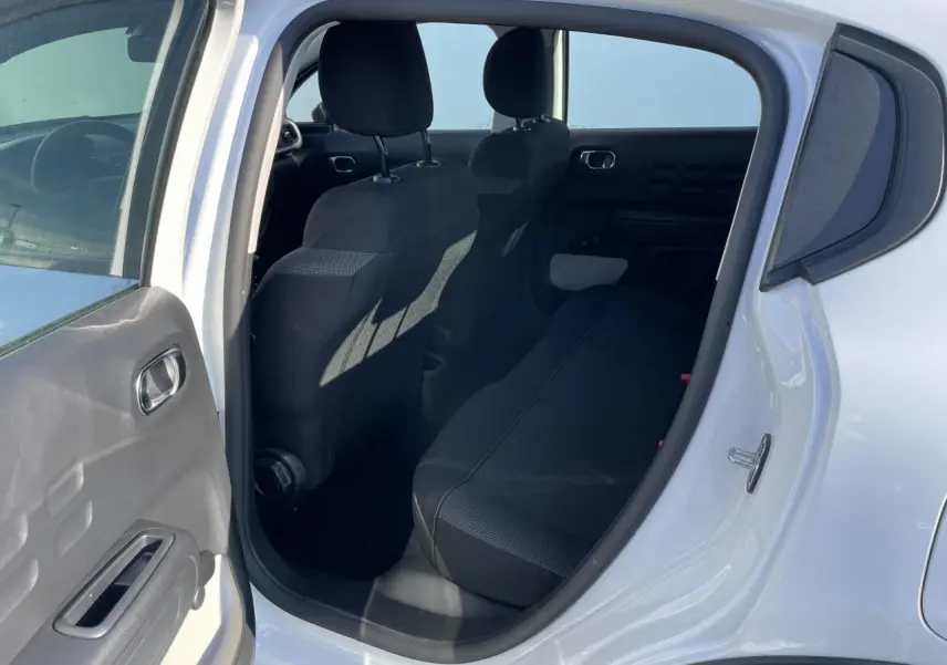 Vue intérieure côté droit de la banquette arrière noire d'une Citroën C3 blanche avec porte ouverte.