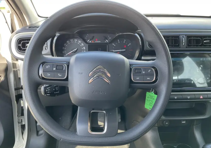 Vue centrée sur le volant noir de la Citroën C3 blanche avec tableau de bord et écran tactile visible à droite.