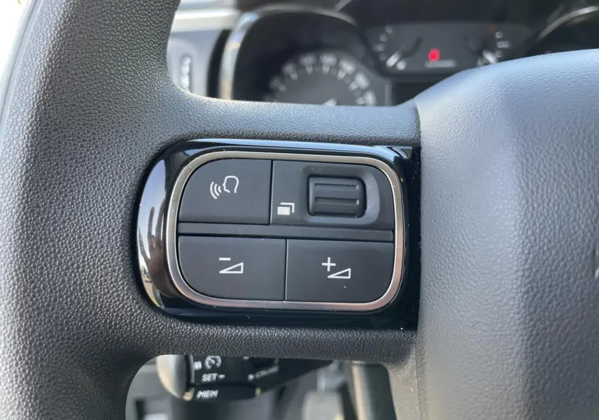Gros plan sur les commandes audio au volant noir brillant de la Citroën C3 blanche, version 2024.