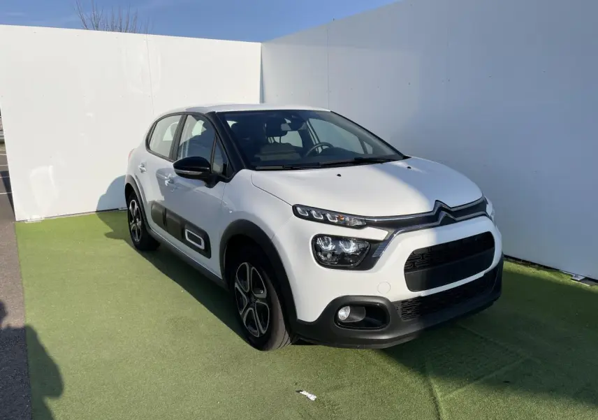 Citroën C3 blanc banquise vue 3/4 avant droit avec protections latérales noires et jantes stylisées.