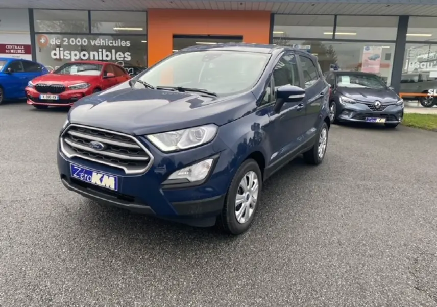Ford EcoSport bleu abysse en 3/4 avant droit, avec calandre chromée et feux de jour LED visibles sur parking.