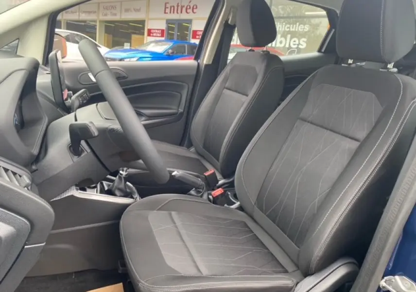 Vue intérieure côté conducteur du Ford EcoSport bleu abysse 2022, montrant les sièges avant en tissu noir et la boîte manuelle.