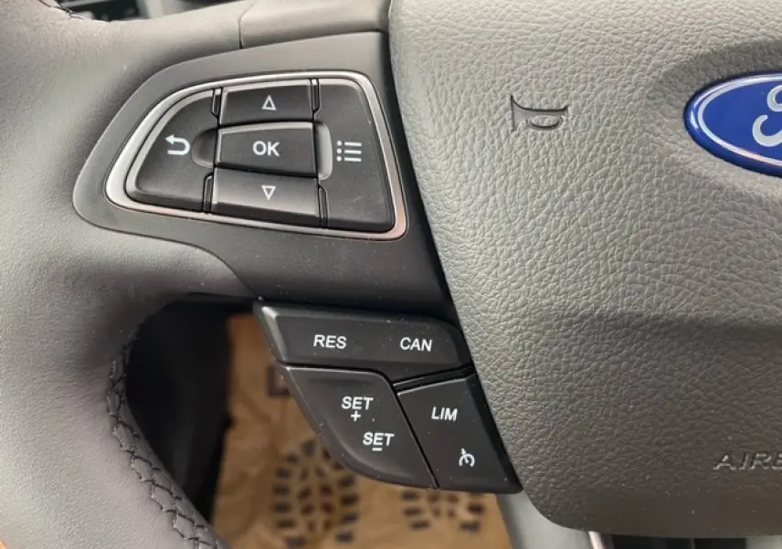 Gros plan sur les commandes au volant côté gauche du Ford Ecosport bleu Abysse, montrant les boutons de régulateur de vitesse.