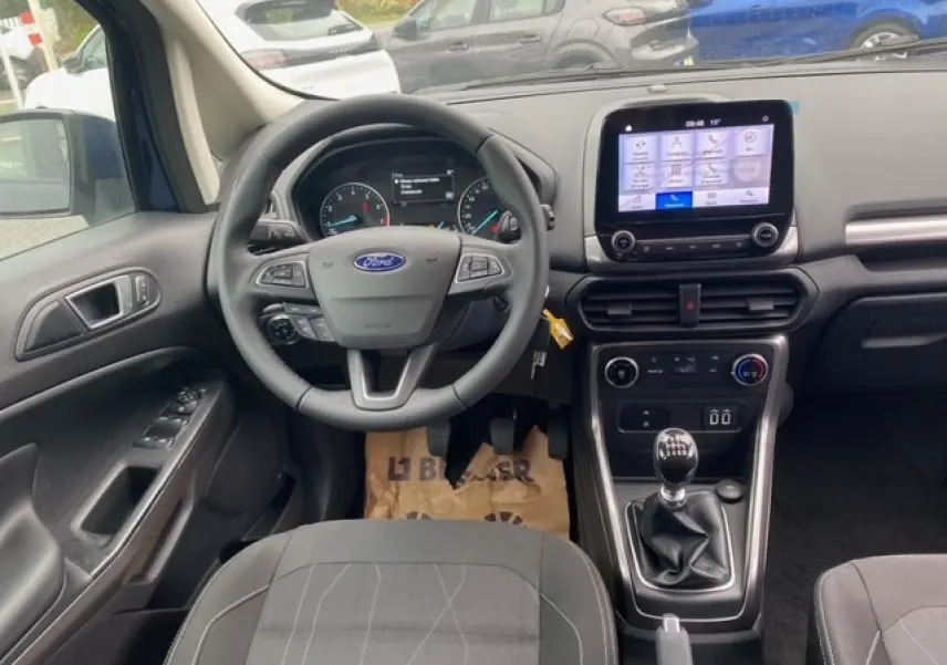 Vue intérieure avant du Ford EcoSport bleu Abysse 2022, tableau de bord avec écran tactile et boîte manuelle.