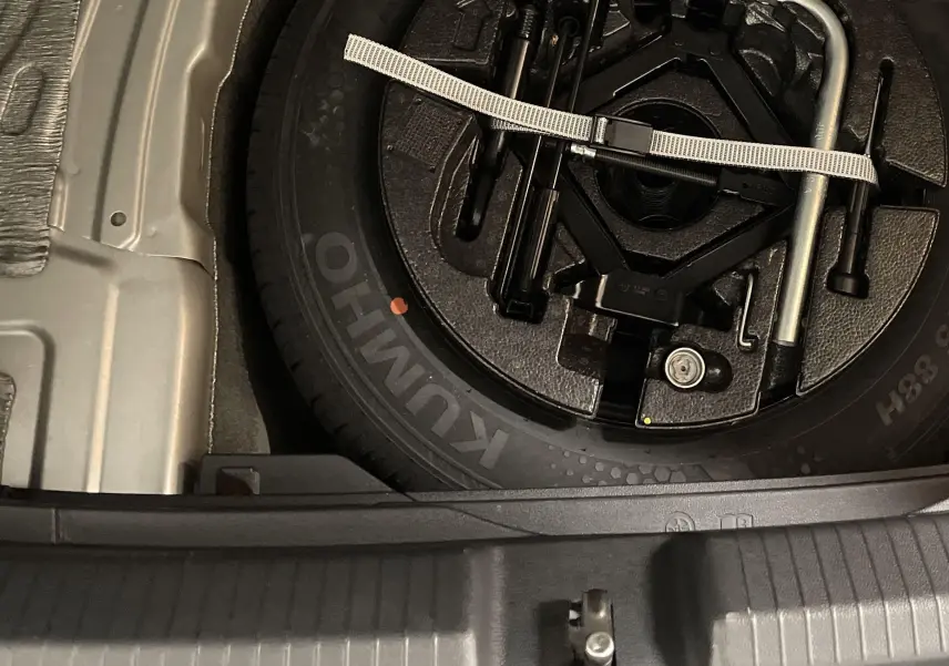 Gros plan sur la roue de secours acier et outillage de bord dans le coffre d'une Volkswagen Polo 2023 argentée.