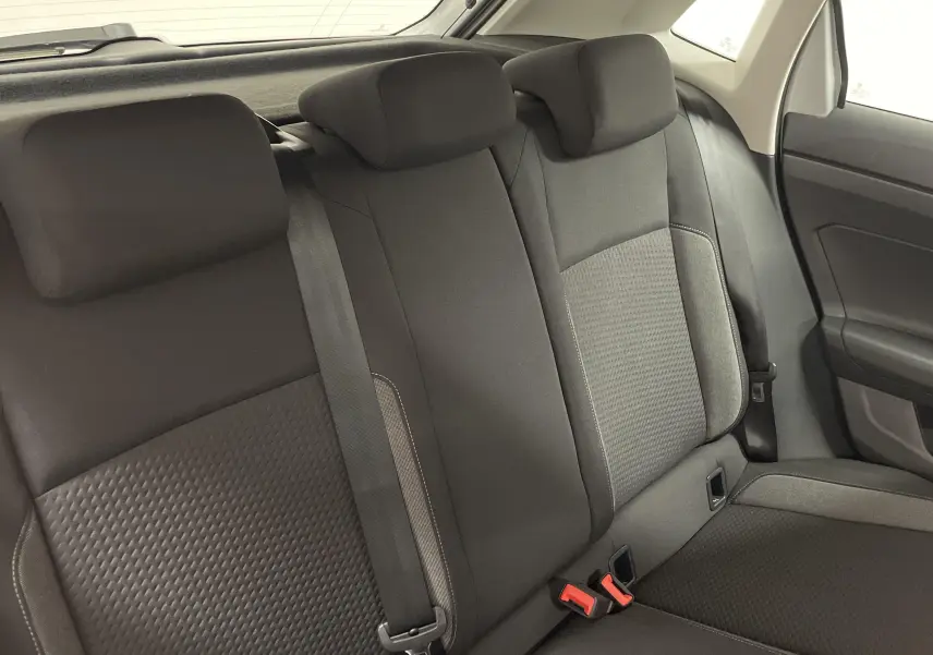 Vue intérieure sur les sièges arrière noirs d'une Volkswagen Polo 2023, avec ceinture de sécurité et garniture de porte visible.