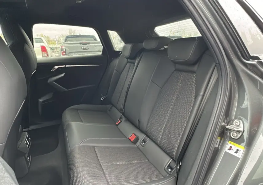Vue intérieure arrière montrant les sièges en cuir tissu gris d'une Audi A3 2025 finition S-Line avec porte ouverte côté droit.
