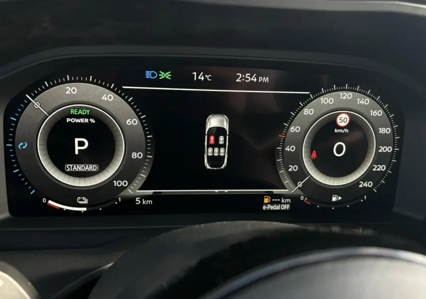 Tableau de bord numérique du Nissan Qashqai 2025, affichage central avec compteurs ronds et alertes visibles.