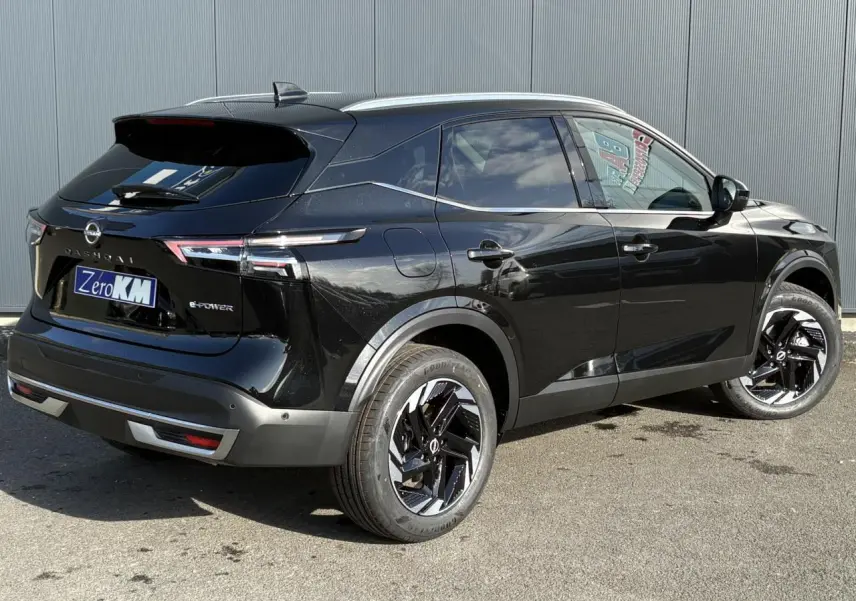 Vue 3/4 arrière droite du Nissan Qashqai III e-Power noir avec jantes alliage noires et barres de toit chromées.