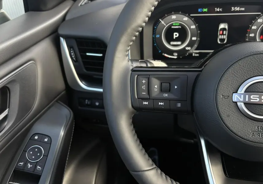 Gros plan sur le volant cuir et la porte côté gauche du Nissan Qashqai noir, avec tableau de bord numérique visible.