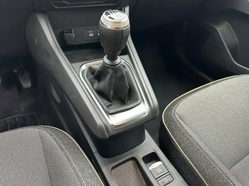 Vue rapprochée de la console centrale du Renault Captur 2025, montrant le levier de vitesse manuel et les sièges gris avec surpiqûres jaunes.