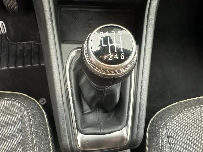 Gros plan sur le levier de vitesses manuel noir et chrome du Renault Captur 1.0 Eco-G 2025, entouré de sièges gris.