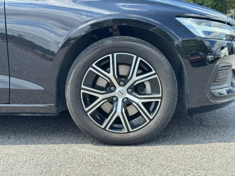 Gros plan sur la roue avant droite et partie avant d'une Volvo S60 gris métallisé avec jante alu au design moderne.