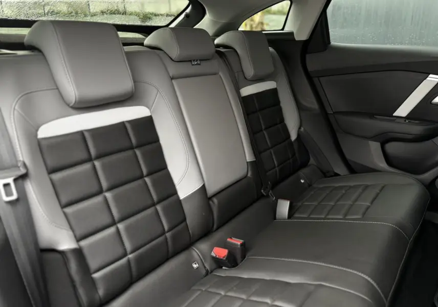 Vue intérieure côté droit des sièges arrière en cuir noir et gris avec surpiqûres blanches de la Citroën C4 Hybrid 2025.
