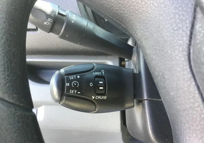 Gros plan sur le commodo de régulateur et limiteur de vitesse noir dans l'habitacle du Citroën Jumpy blanc 2021.