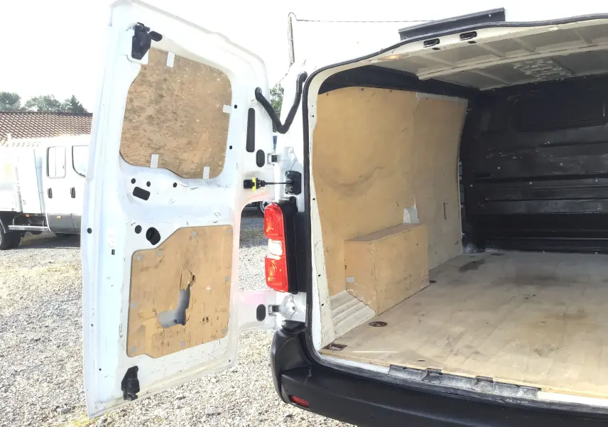Vue arrière ouverte du Citroën Jumpy XL blanc, montrant l'espace de chargement avec revêtement en bois usé.
